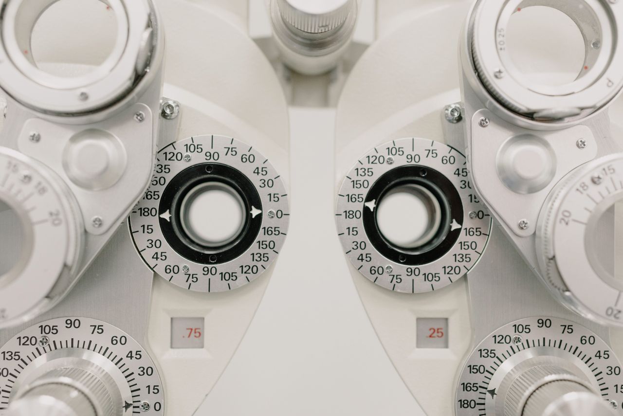 hero-img-01 Modern white ophthalmic phoropter with optometric glasses for measuring eyesight made of metal placed on white background in contemporary clinic
