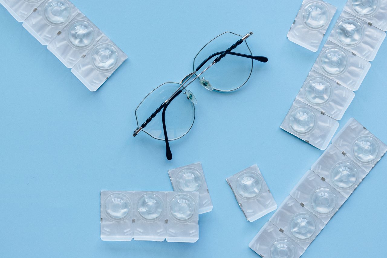 about-01 Eyeglasses and contact lenses on a blue background. Concept of eye care and vision correction.
